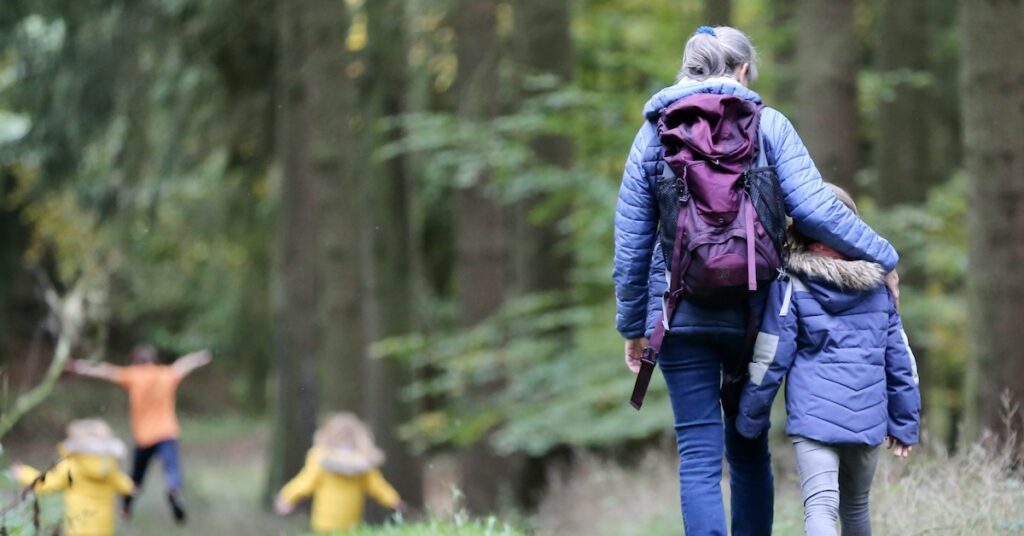 An adult and four children walking in nature. 